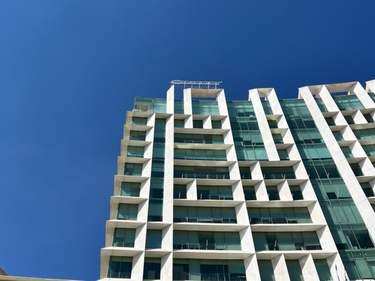 a tall white building with balconies against a blue sky