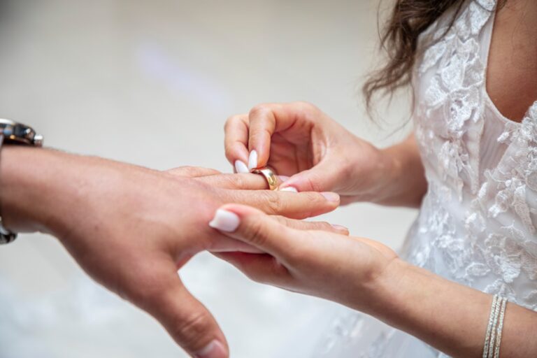 a bride putting a wedding ring on a groom's finger