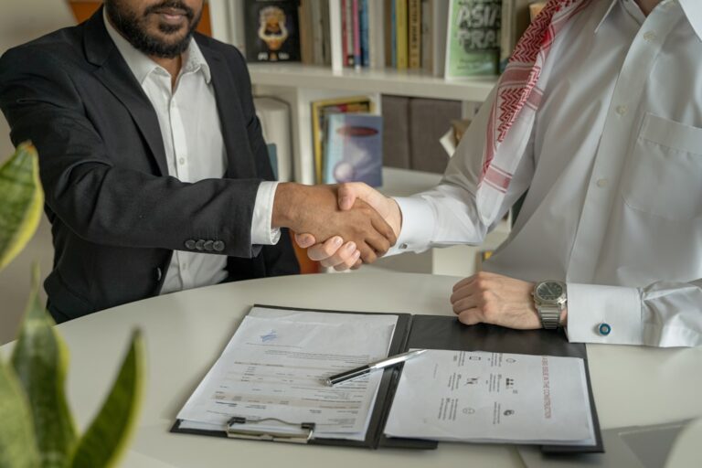 a couple of men shaking hands over a desk